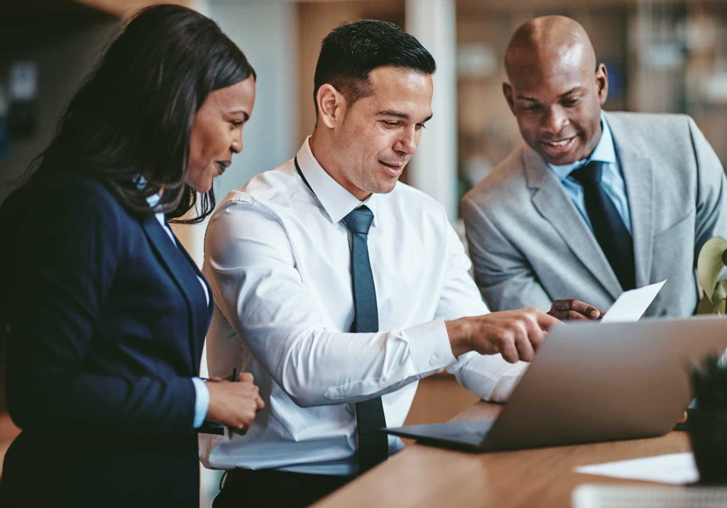 Trois employés discutant sur un projet devant leur ordinateur portable